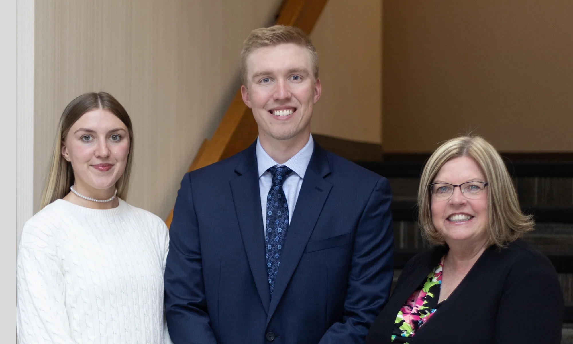 Three staff members of Monroe & Company CPAs posing for a photo indoors; two women on either side of a man in a suit.